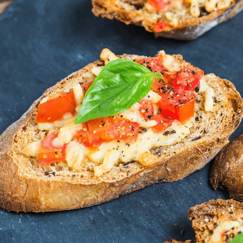 Close-up of Mario's Italian Restaurant's bruschetta with melted cheese, diced tomatoes, and fresh basil.